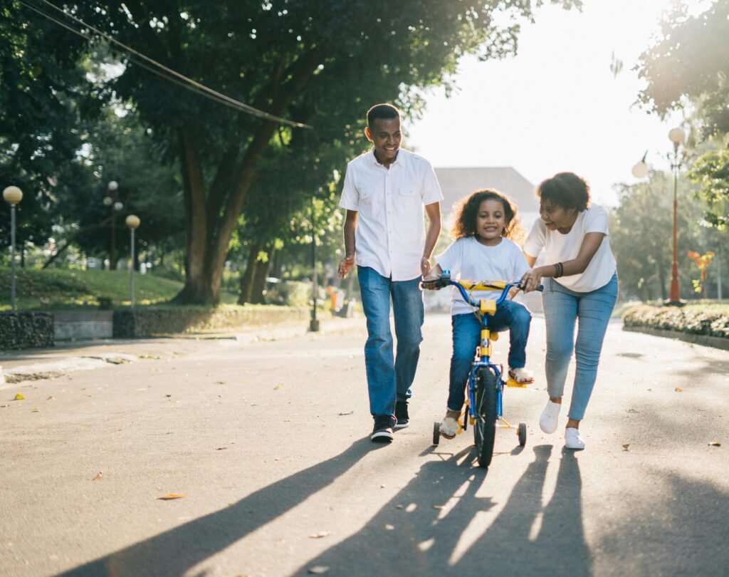 Family Cycling Outdoors Happy family teaching their child to cycle on a sunny day outdoors.