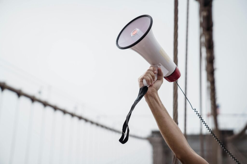 pexels-photo-8898633-8898633 A hand holding a megaphone, symbolizing protest or announcement at an outdoor rally.